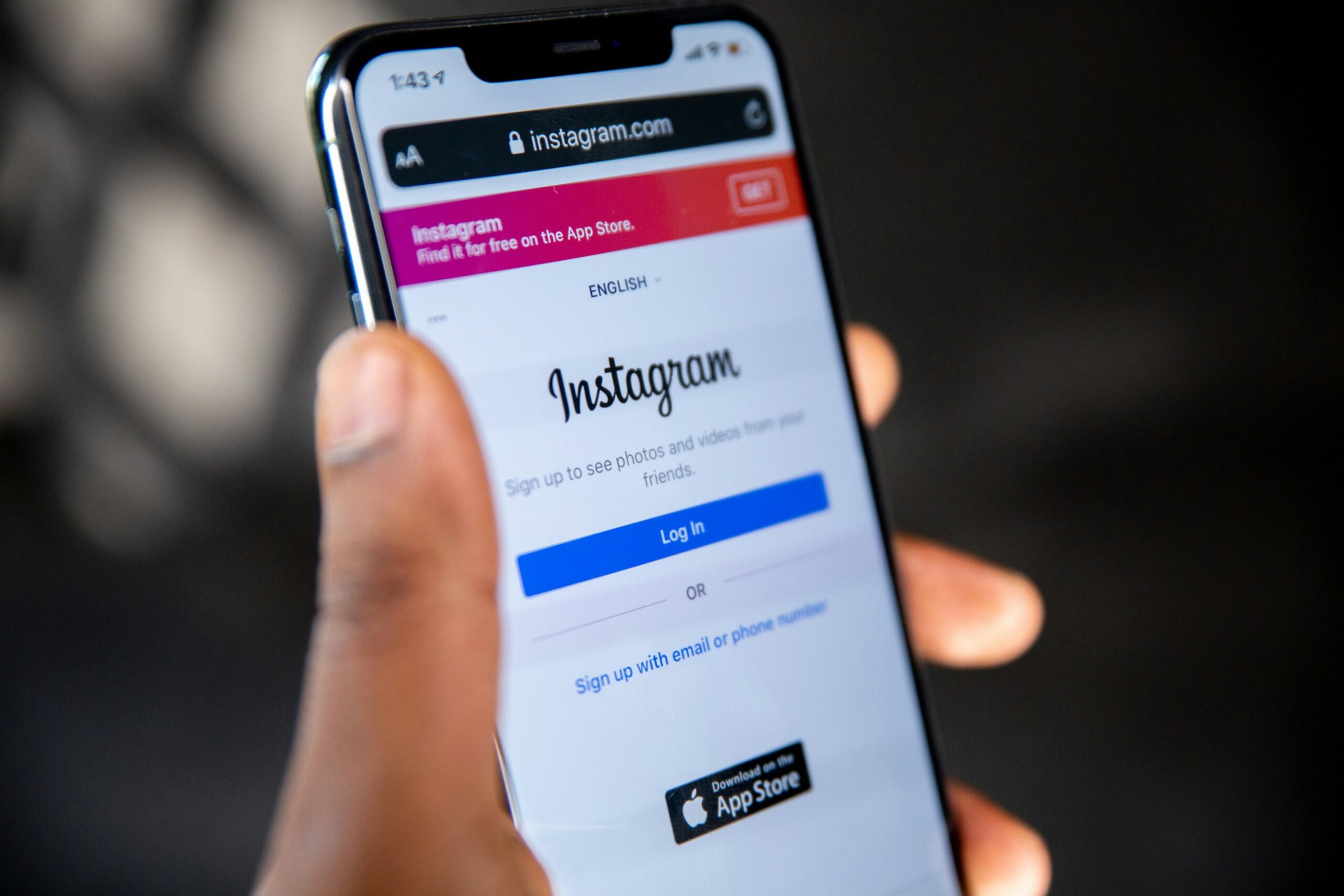 Person holding a smartphone with the Instagram login page open on the screen.