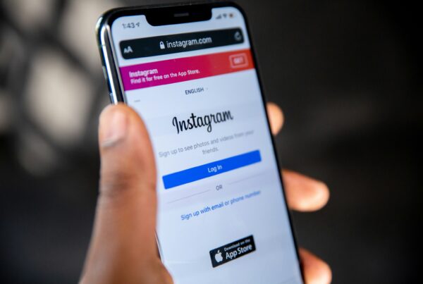Person holding a smartphone with the Instagram login page open on the screen.